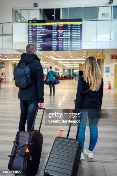 couple check flight at the international airport. - travel cancellation stock pictures, royalty-free photos & images