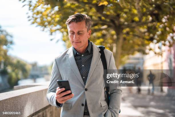 handsome mature salesman using a smart phone to work on the go - forens stockfoto's en -beelden