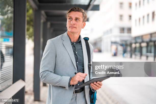 handsome caucasian male financial advisor working with a digital tablet while commuting in the city - case manager stock pictures, royalty-free photos & images