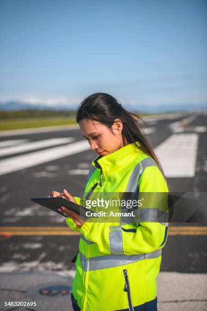 asian female airfield operations officer using a digital tablet - airport ground crew uniform stock pictures, royalty-free photos & images