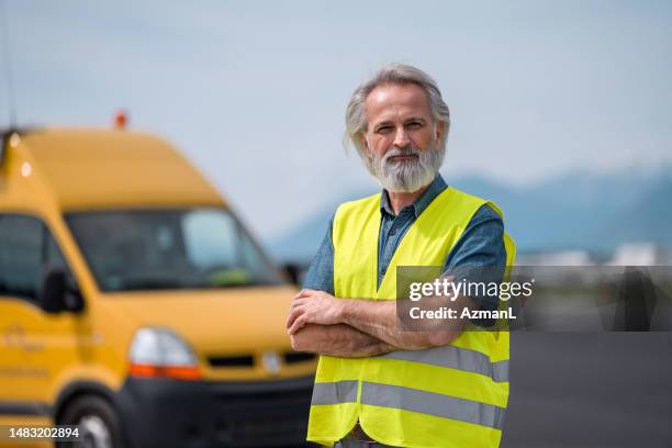 bearded caucasian airport engineer with hands crossed - airport ground crew uniform stock pictures, royalty-free photos & images