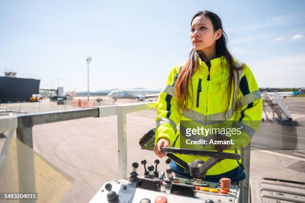 asian female airport worker operating a container transporter - transporter stock pictures, royalty-free photos & images
