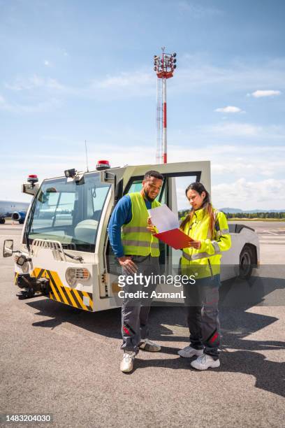 travailleurs d’aéroport debout devant un véhicule tracteur sur une piste - piste daéroport photos et images de collection