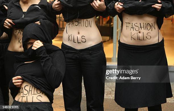 Young activists from the labor rights group ver.di show their stomachs with the words "Fashion Kills" written on them during a demonstration in the...