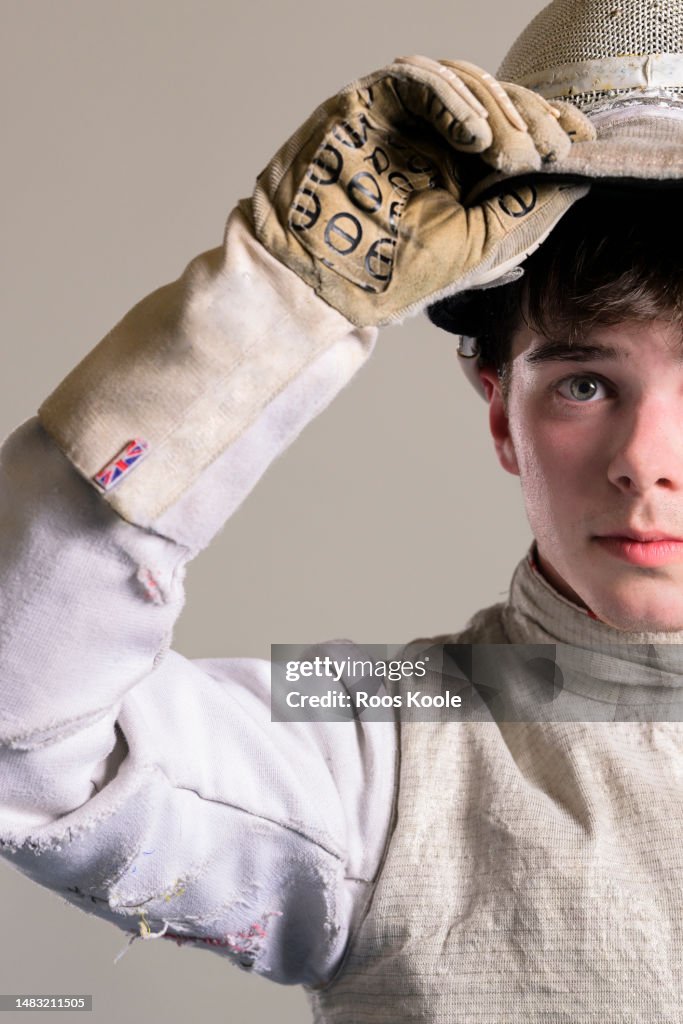 Portrait of a teenage boy holding his fencing mask