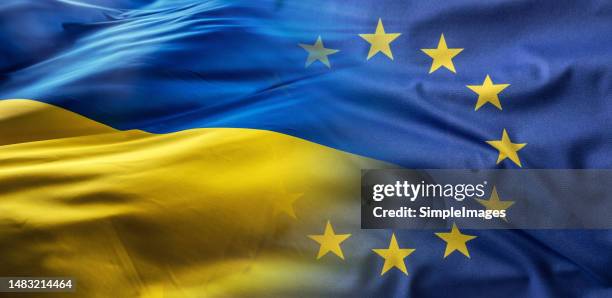 european union and ukrainian flags flutter together in the wind. - kiew stock-fotos und bilder