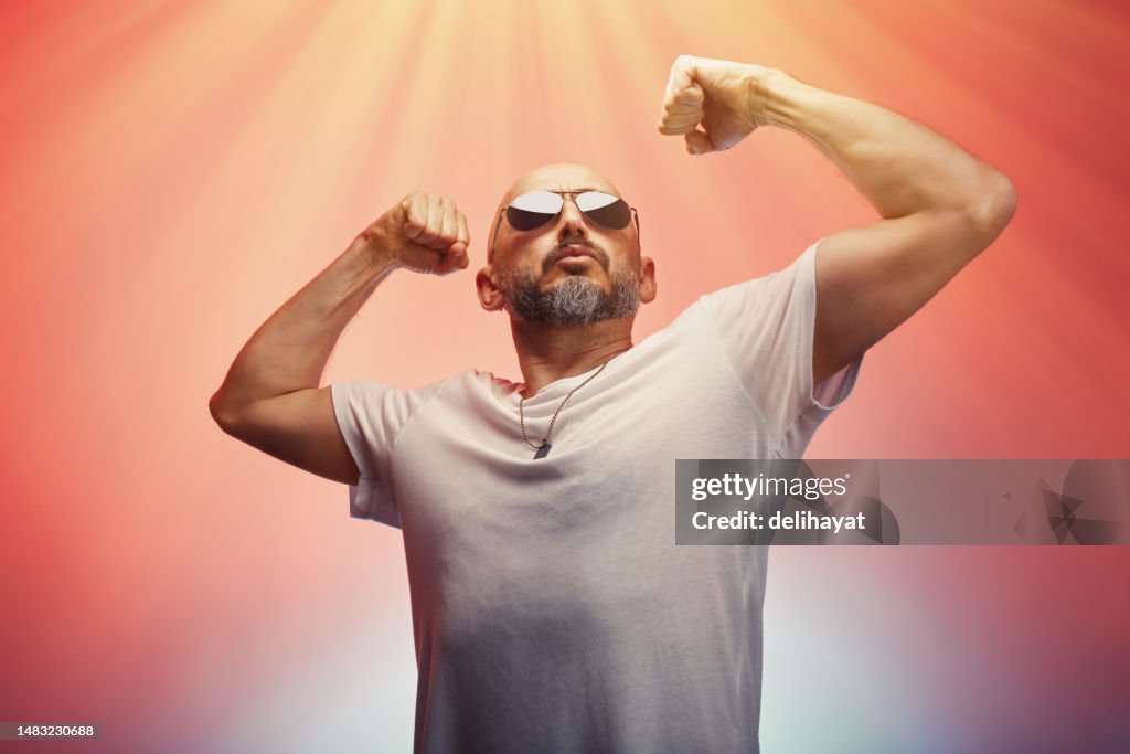 Man flexing his arms muscles and biceps showing his strength and male power, colorful background
