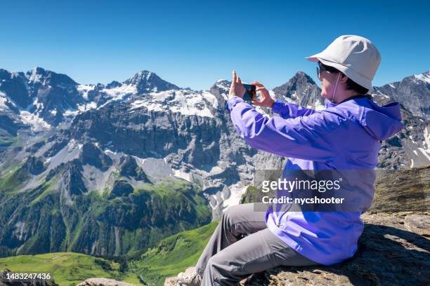 switzerland travel - seniorin macht ein foto von den schweizer alpen - korean ethnicity stock-fotos und bilder