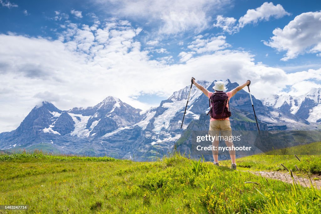Switzerland Travel - Senior Asian woman, with arms extended, enjoying the majestic views when hiking through the Swiss Alps in the Jungfrau region