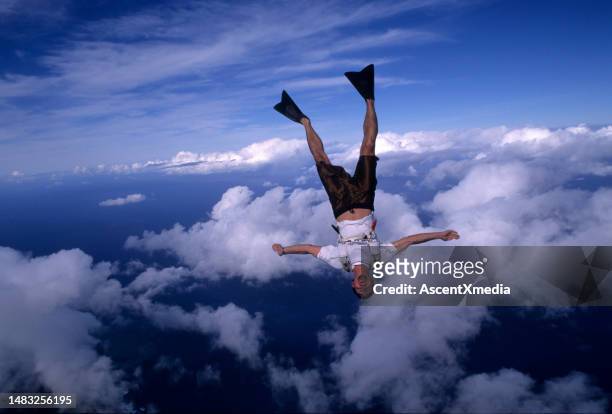 skydiver with flippers free falls above clouds and sea - aerial stunts flying stock pictures, royalty-free photos & images
