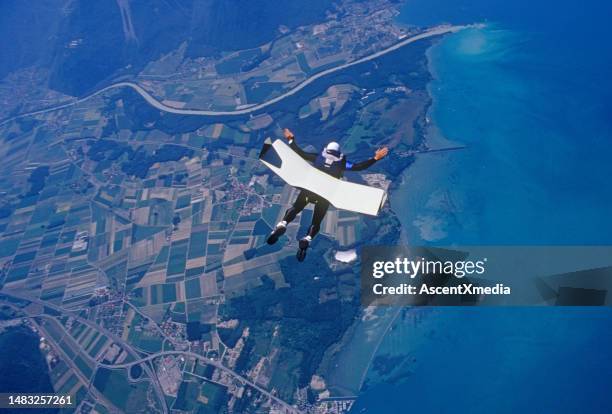 skydiver glides with skyboard above coastline - super excited suit stock pictures, royalty-free photos & images