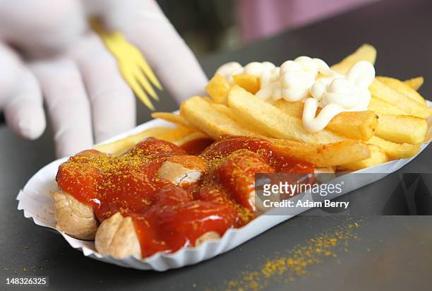 An employee puts a small plastic fork into a plate of currywurst with french fries at Konnopke's currywurst stand on July 14, 2012 in Berlin,...