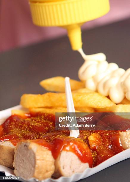 An employee prepares a plate of currywurst with french fries at Konnopke's currywurst stand on July 14, 2012 in Berlin, Germany. Currywurst,...