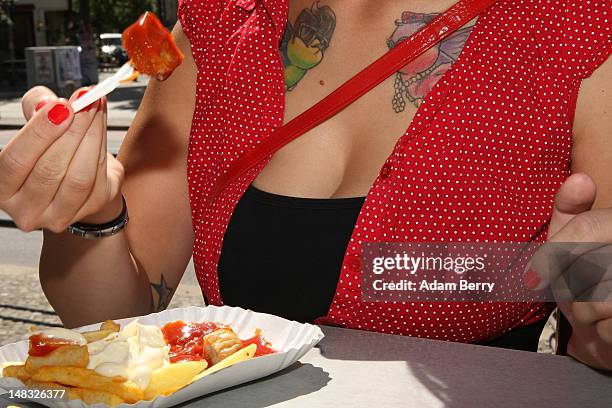 Customer eats a plate of currywurst with french fries at Konnopke's currywurst stand on July 14, 2012 in Berlin, Germany. Currywurst, originally...