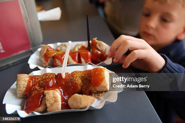 Child takes a plate of currywurst at Konnopke's currywurst stand on July 14, 2012 in Berlin, Germany. Currywurst, originally founded in post-war...