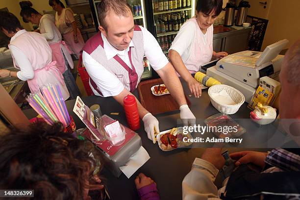 An employee serves a plate of currywurst with french fries at Konnopke's currywurst stand on July 14, 2012 in Berlin, Germany. Currywurst, originally...