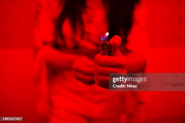 female lighting a lighter in shades of red - cigarette lighter stock pictures, royalty-free photos & images