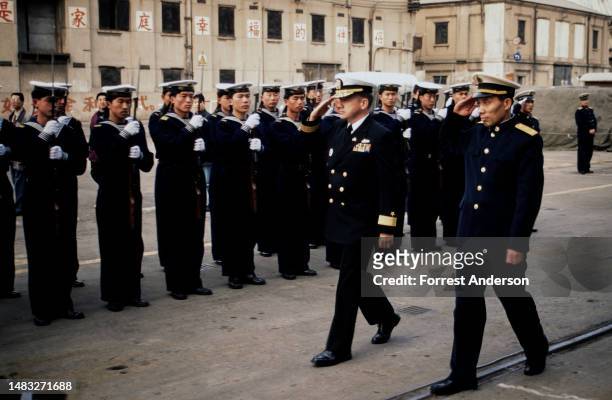 Rear Admiral Walter F Doran & his Chinese counterpart Shao Dewan saluted as they review PLA Navy troops during a dockside welcome for the USS Fort...
