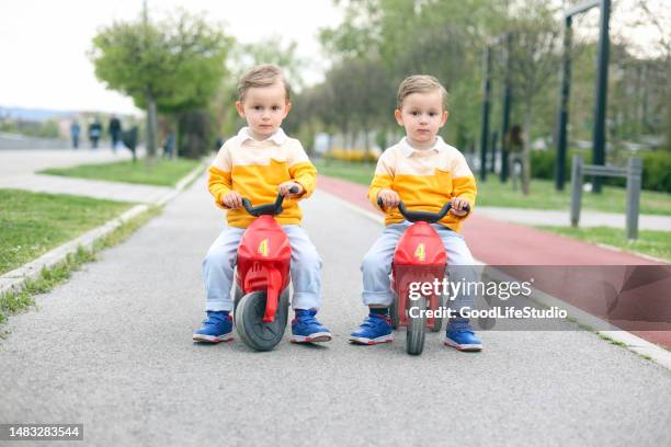 twin brothers driving toy motorcycles - v twin motorcycle stock pictures, royalty-free photos & images