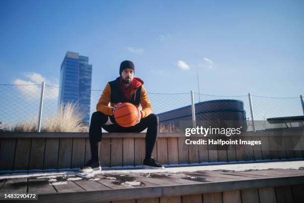 young multiracial man sitting outdoor at basketball playground. - street basketball imagens e fotografias de stock