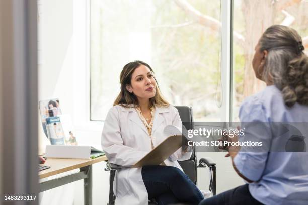 female doctor listens intently to unrecognizable senior woman - listening intently stock pictures, royalty-free photos & images