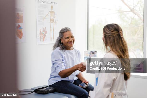 unrecognizable doctor shakes hands with senior female patient - handshake doctor stock pictures, royalty-free photos & images