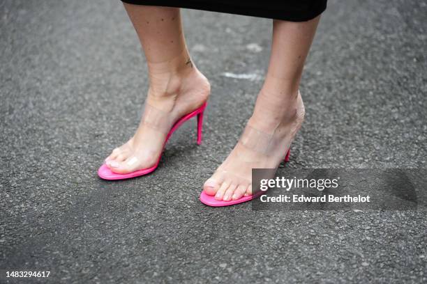 Emy Venturini wears neon pink shiny leather with white transparent plastic large straps heels mules from Louboutin, during a street style fashion...