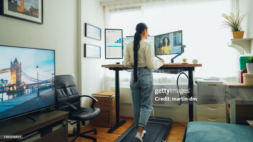 Donna alla scrivania in piedi home office che parla in videochiamata aziendale