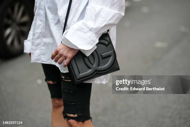 Emy Venturini wears a white oversized shirt from Cos, black ripped denim skinny shorts, a black shiny leather embossed DG logo shoulder bag from...