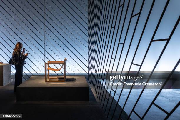 Woman uses her phone to take a picture of an armchair part of the design exhibition “Il potere dell’essenziale” by Hermes at La Pelota Jai Alai,...