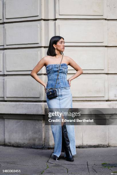 Angela Gonzalez wears gold earrings, a blue faded denim shoulder-off/ buttoned ripped corset top, a black shiny leather small Coco Handle handle...