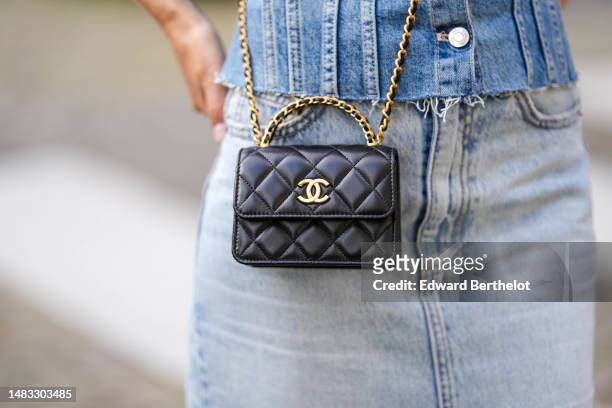 Angela Gonzalez wears a blue faded denim shoulder-off/ buttoned ripped corset top, a black shiny leather small Coco Handle handle crossbody bag from...