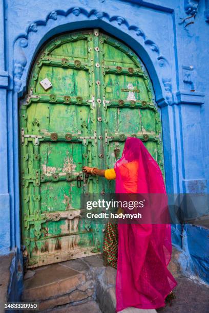 young indian woman walking inside a blue city of jodhpur, india - woman in red sari stock pictures, royalty-free photos & images