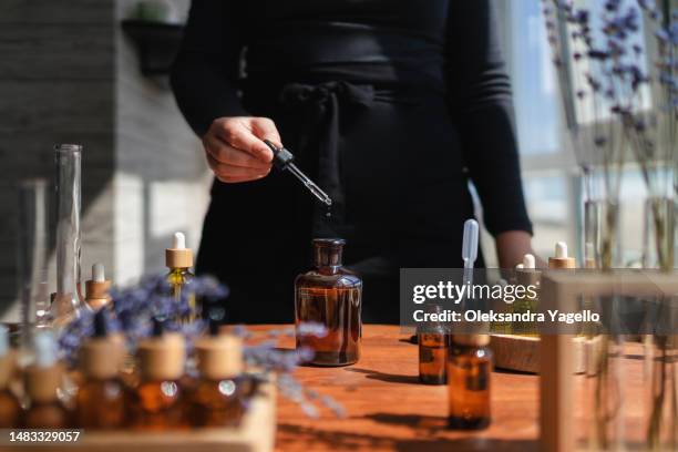 woman preparing aromatic liquid for diffuser. the process of creating perfume, workshop - perfume stock-fotos und bilder