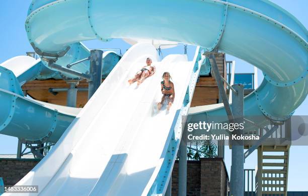 happy cheerful kids splashing water on water slide at aqua park - wasserrutsche stock-fotos und bilder