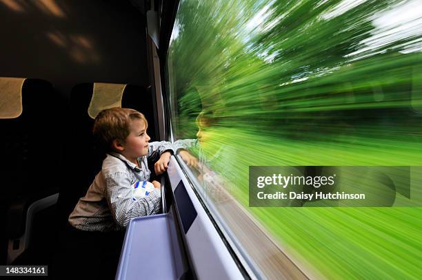 boy looking out of train window - bambino treno foto e immagini stock