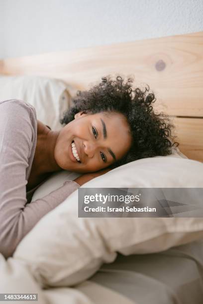 portrait of newly awakened beautiful woman lying in bed, smiling looking at camera. - woman pillow stock pictures, royalty-free photos & images
