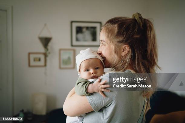 mum holding baby on shoulder and looking out window - new mum stock-fotos und bilder