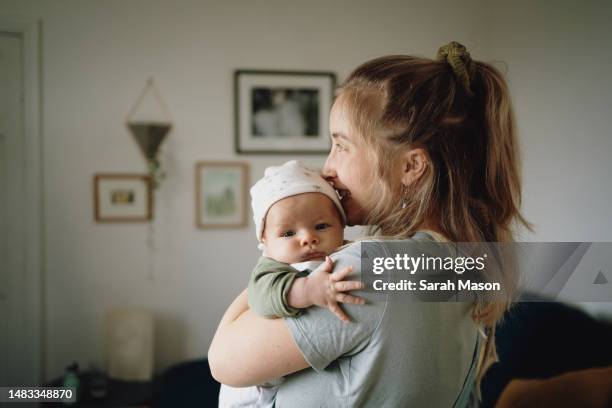 mum holding baby on shoulder and looking out window - baby imagens e fotografias de stock
