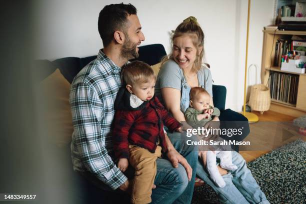 young couple with small children smiling lovingly at each other - babyhood stock pictures, royalty-free photos & images