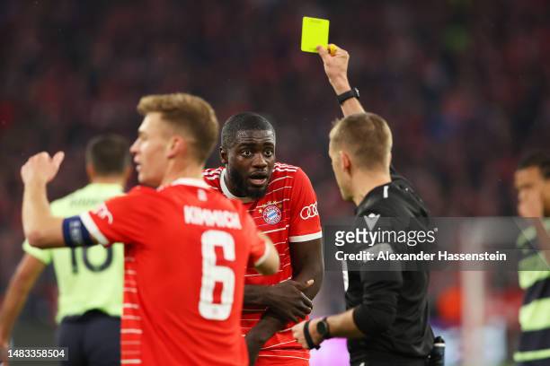 Dayot Upamecano of FC Bayern Munich is shown a yellow card by Referee Clement Turpin for handball leading to a penalty being awarded to Manchester...
