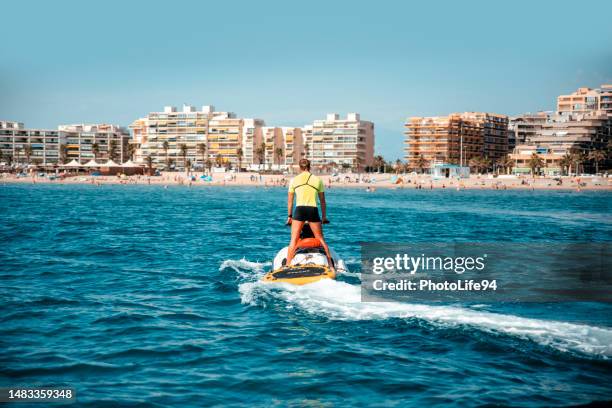 lifeguard man on summer work skillfully maneuvering a jet ski - surf rescue stock pictures, royalty-free photos & images