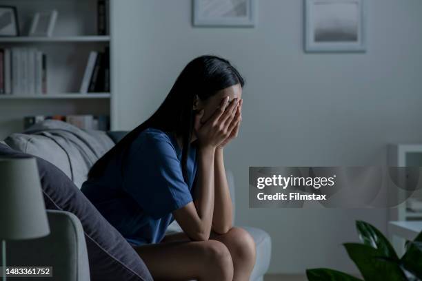 young asian woman sitting on sofa at home feeling sad tired and worried suffering depression in mental health. - asian woman sitting alone stock pictures, royalty-free photos & images