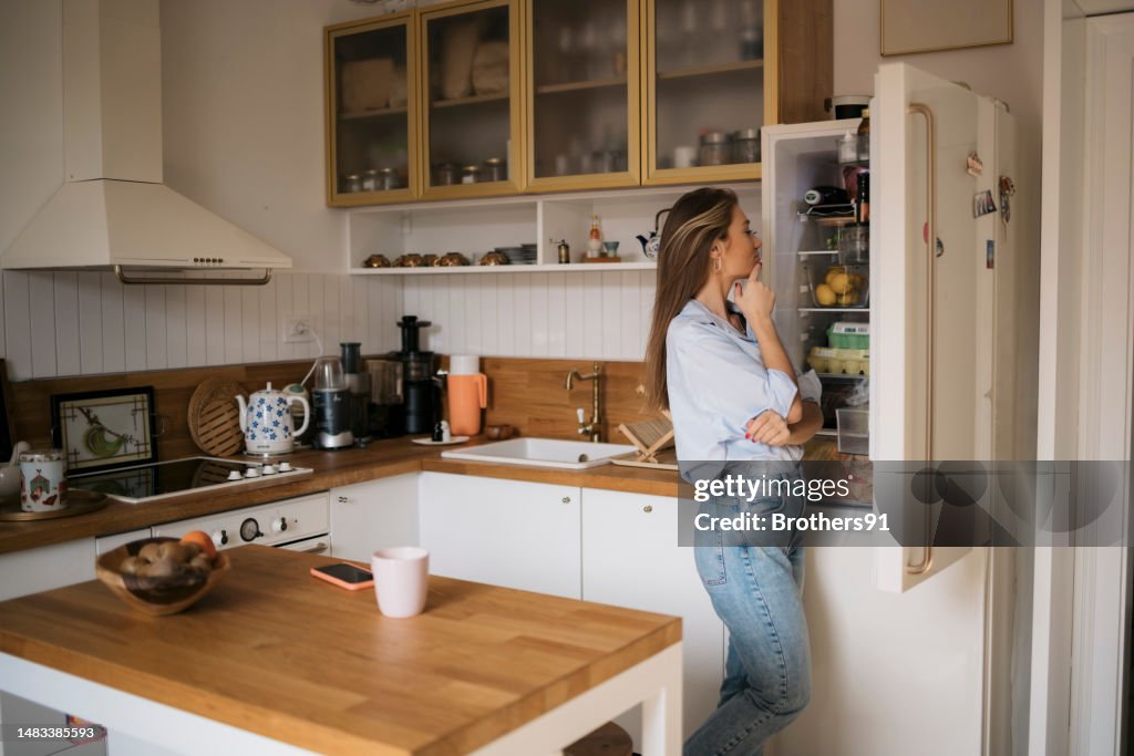 Young woman searching food inside a refrigerator at home