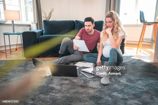 young caucasian pregnant couple revising their finances at home - money decisions stock pictures, royalty-free photos & images