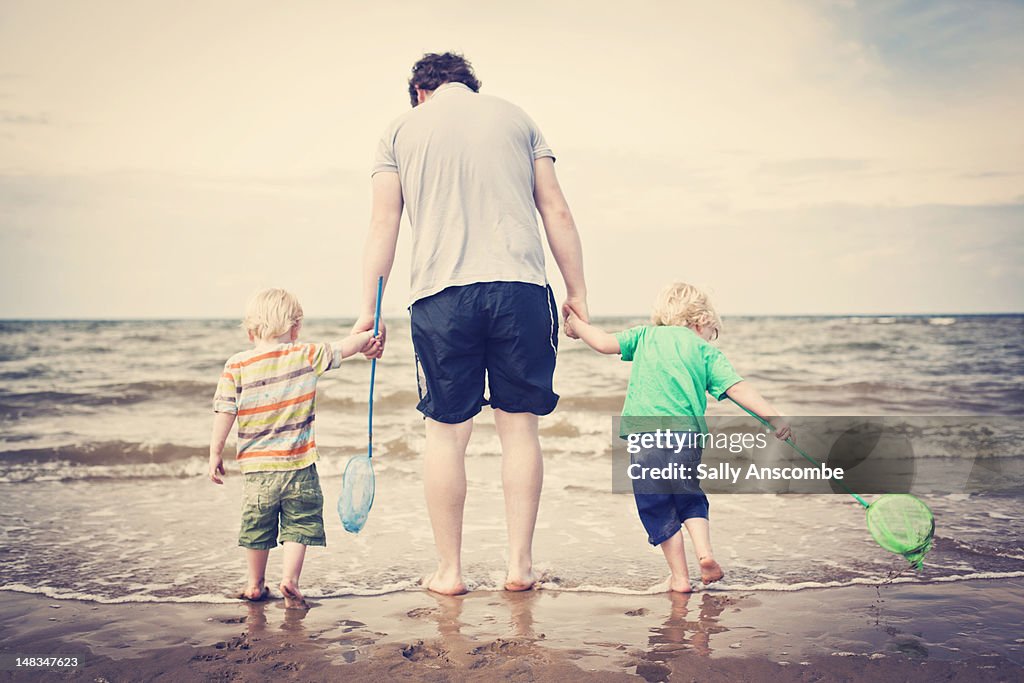 Two children paddling in sea with daddy
