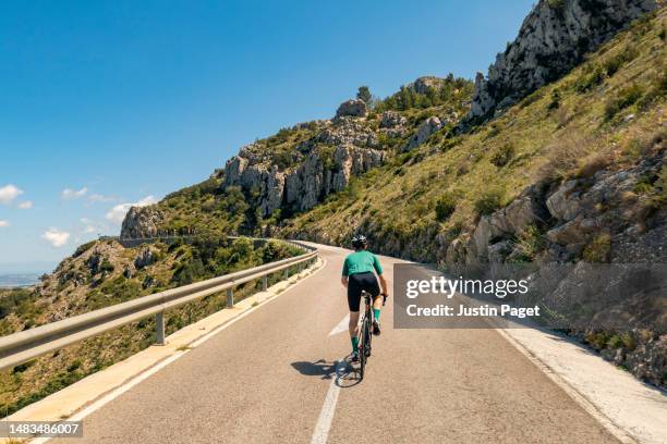 rear view of a cyclist climbing in the spanish mountains - uphill stock-fotos und bilder