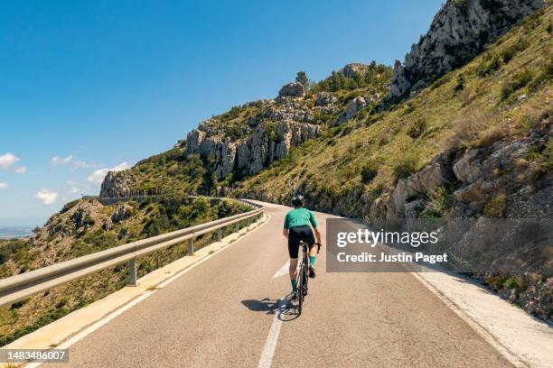 rear view of a cyclist climbing in the spanish mountains - ciclista foto e immagini stock