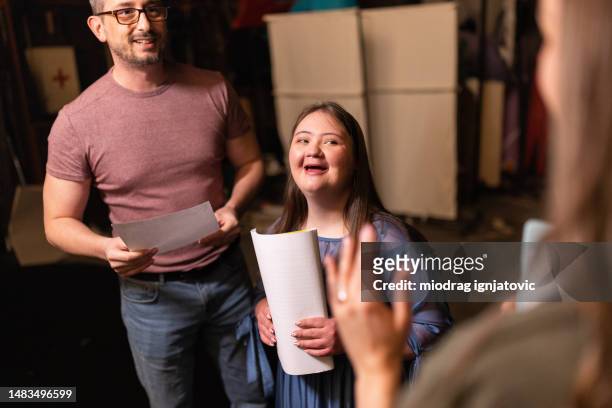 young woman with down syndrome practicing her lines with her colleagues before a performance - small group of people stock pictures, royalty-free photos & images