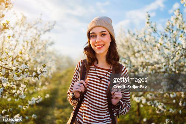 spring portrait of beautiful smiling young woman standing in blossoming orchard - april 22 stock pictures, royalty-free photos & images